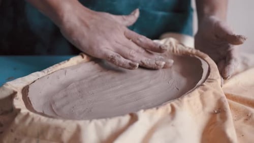 Hands Shaping Clay into Plate in Studio