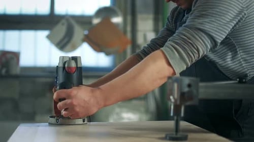 Tradesman Using Router on Wood Surface in Workshop
