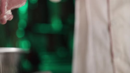 Chef sprinkles flour on counter top to prevent food from sticking during preparation. Close up shot.