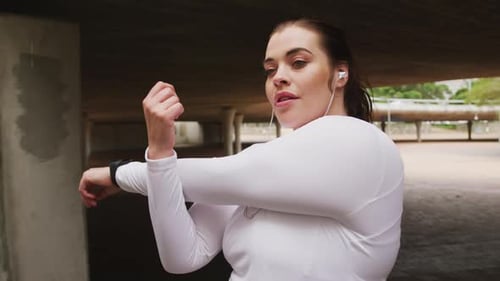 Young Woman Stretching Arm Under Overpass
