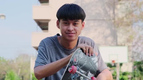 Young Man Poses with Skateboard in Urban Setting