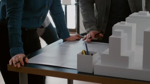 Close Up of Colleagues Working on Urban Design with Blueprints and Building Model