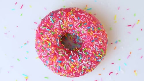 Delicious Sweet Donut Rotating on a Plate. Top View. Bright and Colorful Sprinkled Donut Close-up