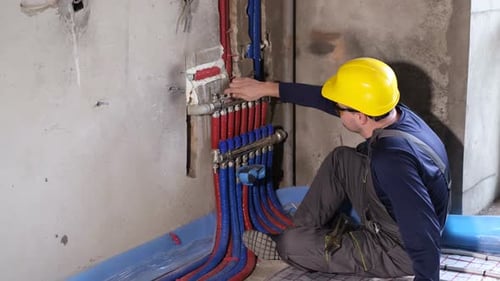 Handsome Young Plumber Fixes Valves in the Boiler Room