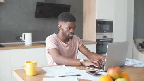 Young Adult Working on Laptop in Modern Kitchen