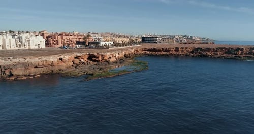 Drone Flies Above Blue Water of Sea Along the Coast Overlooking City at Morning