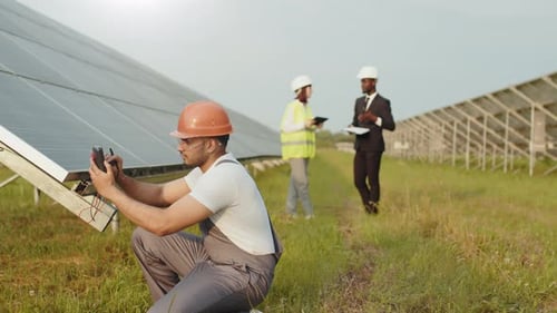 Energietechniker in Helm und Uniform mit Multimeter zur Spannungsmessung