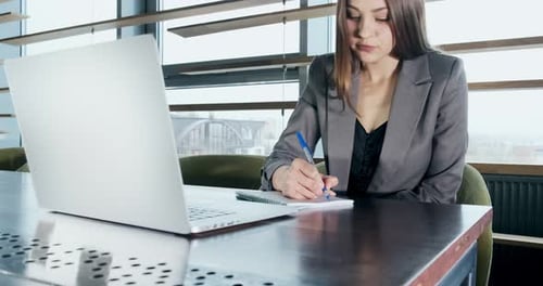 Concerned Woman Working on Laptop Computer and Looking Away Thinking Solving Problem at Office