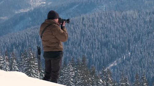 Man Photographs Snow Covered Mountains in Winter