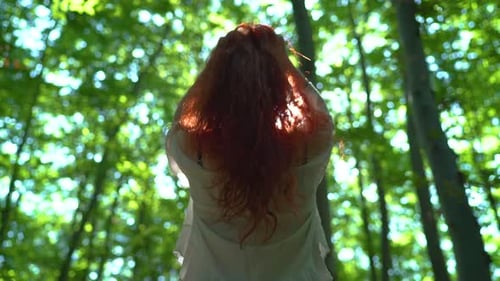 Woman with Long Red Hair in Green Forest
