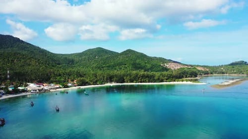 Calm turquoise lagoon reflecting white clouds on bright blue sky on beautiful shore of tropical isla