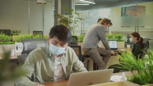 Un jeune homme travaille et ses collègues discutent d'un projet