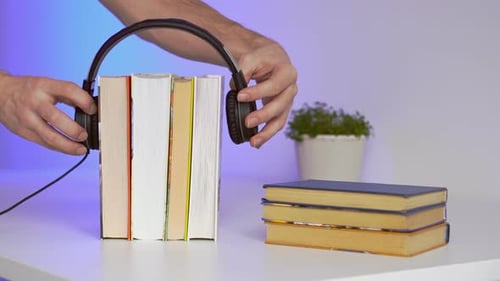 Schwarze Kopfhörer mit Bücherstapel auf blauem Hintergrund. Hörbücher oder Bildungskonzept.