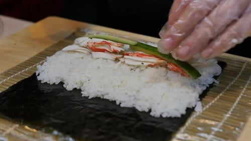 Preparing Sushi Roll with Crab and Cucumber