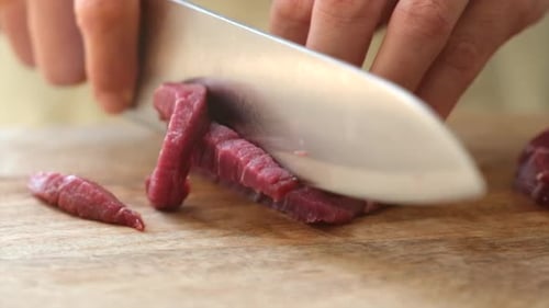 Ernte-Frau schneidet Fleisch in der Küche