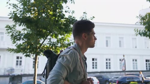 Attractive Young Handsome Man Tourist with Backpack Walking in City Center and Looking Around Slow