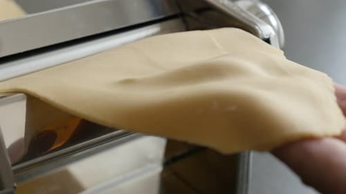 Hand Feeding Dough Through Pasta Machine Close Up