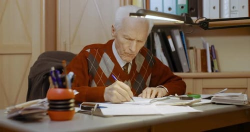 Senior Geschäftsmann schreibt auf Papier am Tisch im Büro