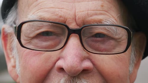 elderly senior man opening eyes looking at camera and smiling, close-up portrait face