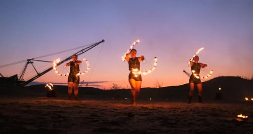 Feuershow Drei Frauen in ihren Händen drehen brennende Speere und Fächer im Sand mit einem Mann mit zwei