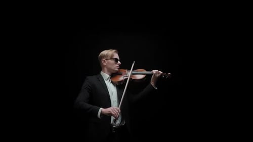 Young Caucasian Male in Black Suit and Glasses Plays Violin on Dark Background