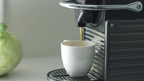 Coffee Maker Dispenses Espresso Into a White Cup