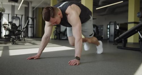 Young Muscular Athlete Works Out in Modern Gym Making Mountain Climbers Exercise