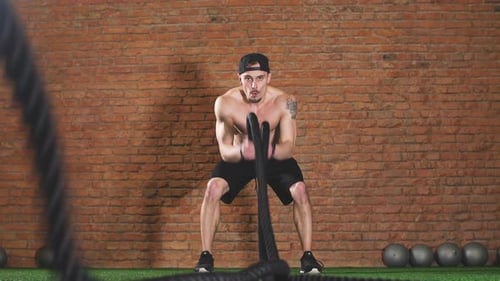 Man with Battle Rope Battle Ropes Exercises in Fitness Gym. Cross Fit Concept