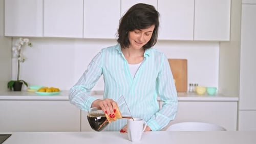 Woman Pours Coffee in Bright Modern Kitchen
