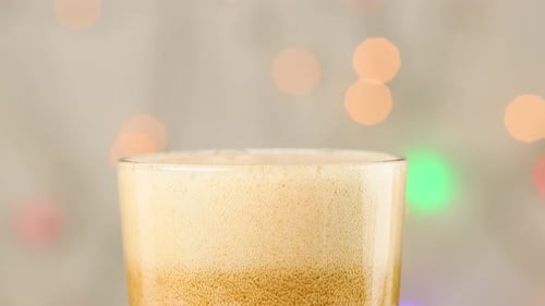 A carbonated sweet drink is poured into a glass. Bubbles close up.