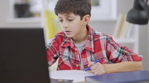 Boy Doing Homework with Laptop at Desk