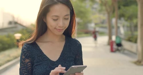 Woman Uses Smartphone During Golden Hour Walk