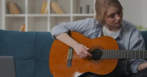 Woman Plays Acoustic Guitar on Couch at Home