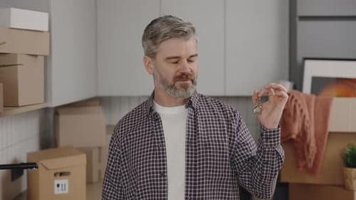 Man Holds Keys Smiling with Moving Boxes at Home