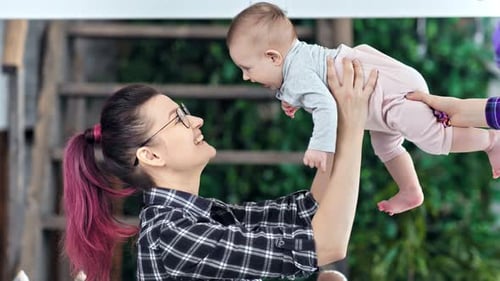 Junge Hipster-Mutter hat Vergnügen, mit ihrer kleinen süßen Tochter zu spielen, mittlere Nahaufnahme