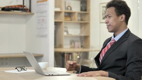 Frustrated Young Adult Working at Laptop in Office