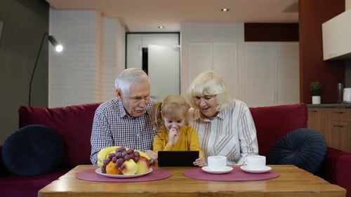 Grandparents and Child Enjoying Tablet Together at Home