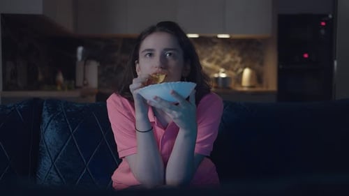 Girl eats chips on couch at night