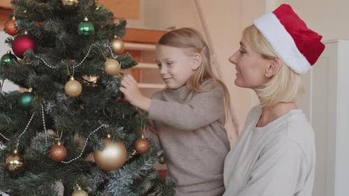 Girl and Mother Decorating Christmas Tree at Home
