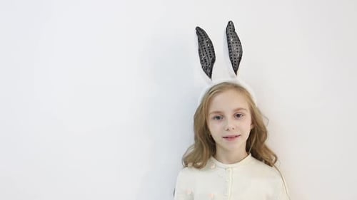 Kleines Mädchen in einem Umhang gekleidet in die Ohren eines Osterhasen Ein glückliches Kind wartet auf das