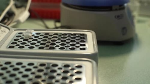 Gloved Hand Placing Vials in Lab Machine
