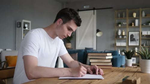 Homme écrivant sur des papiers alors qu'il est assis sur le bureau