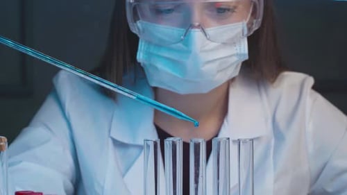 Female Scientist Dropping Samples of Color Liquid Into Test Tubes with Pipette Close Up
