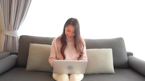 Woman Using Laptop Sitting on Gray Couch