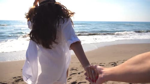 Follow Me Aufnahme einer jungen Frau mit Hut Ziehen Sie ihren Freund an der Küste