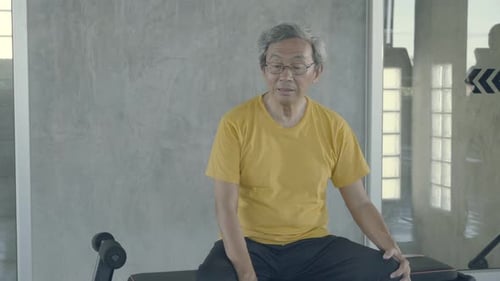 Old man tired after effort exercise in the gym, asia senior sweat sitting expression exhausted.