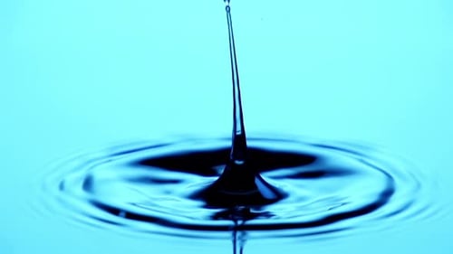 Single Drop Creates Ripples on Blue Water Surface