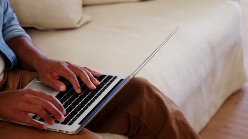 Man Works on Laptop at Home on Couch