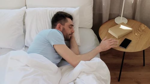 Man Asleep Reaching for Phone in Bedroom