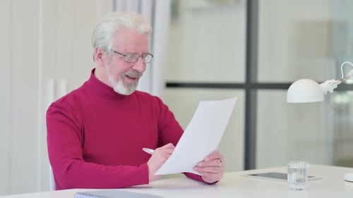 Senior Man Signing Document, Expressing Happiness Indoors